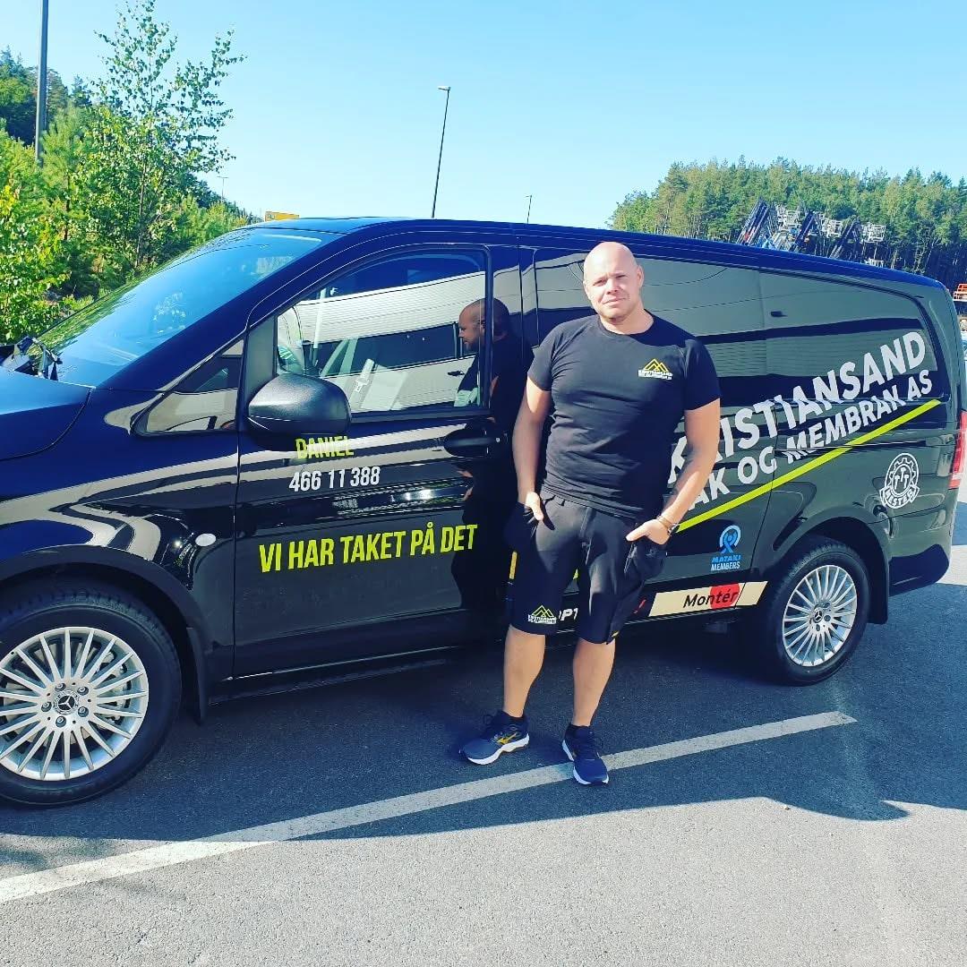 Ansatt foran en av firmabilene, med teksten «Vi har taket på det» på siden