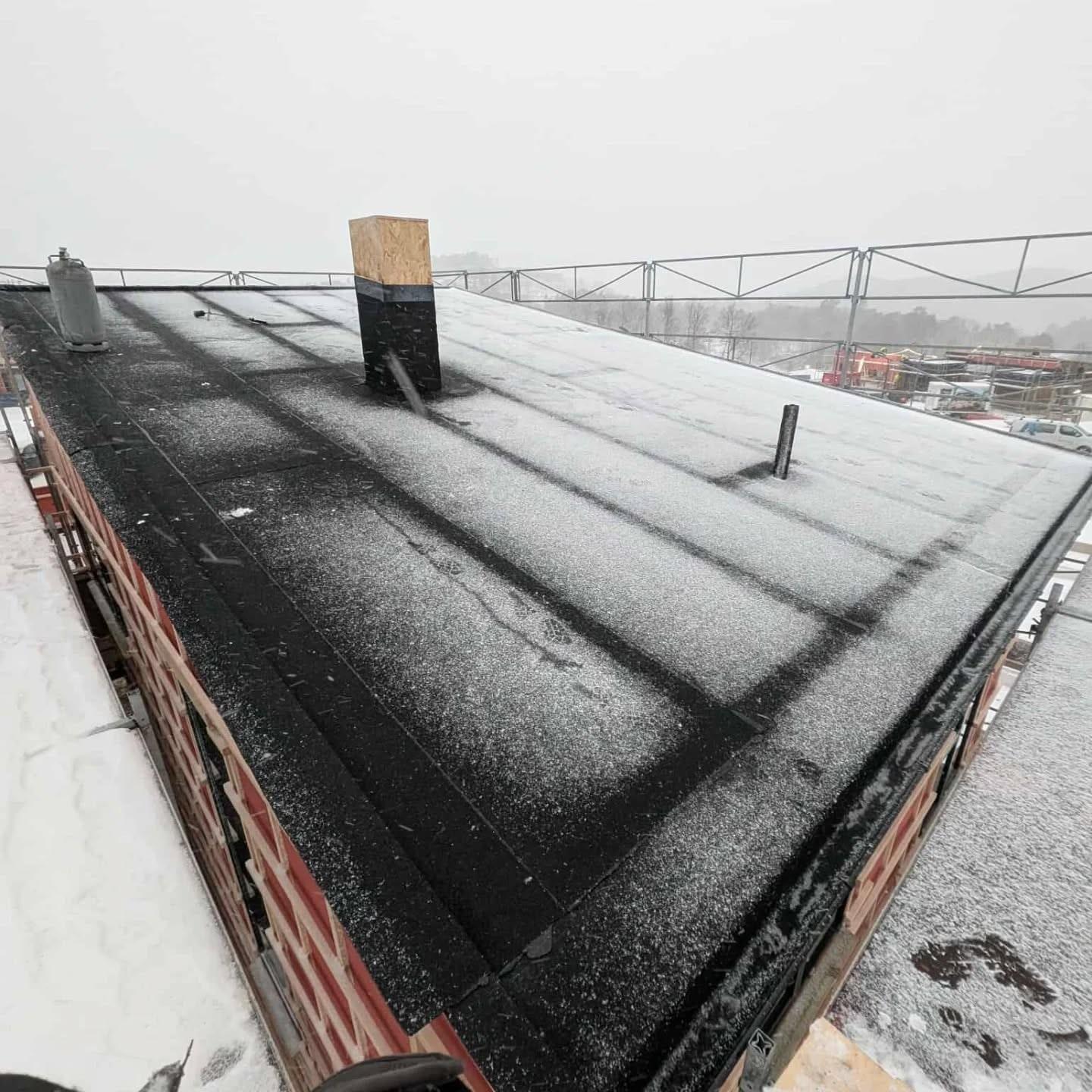 Gammelt flatt tak med snø, under arbeid